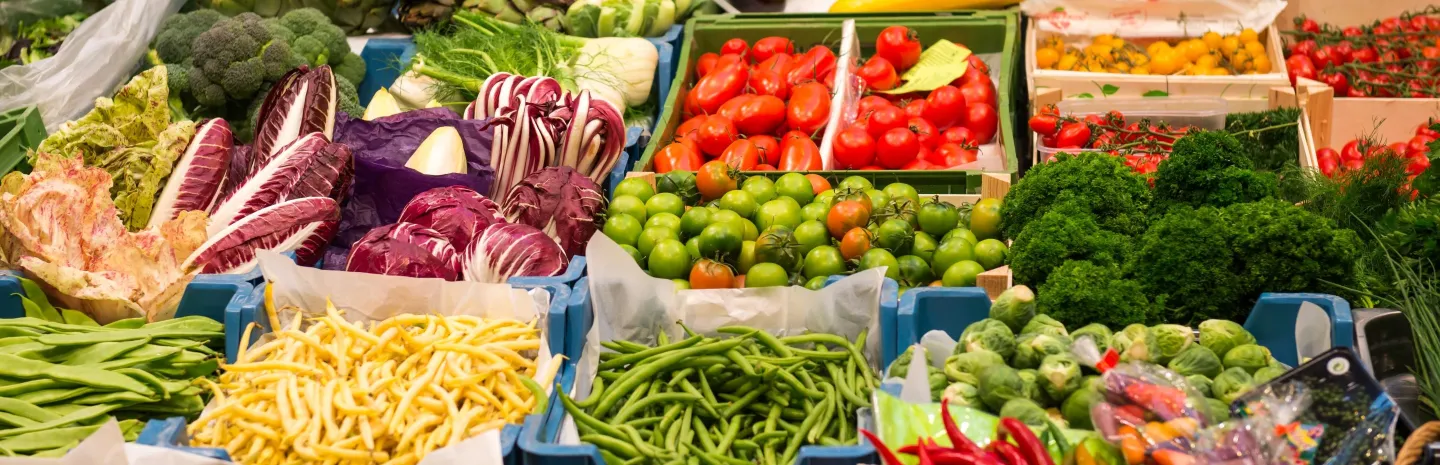 A produce market stall with a variety of colorful seasonal fruit and vegetables on offer