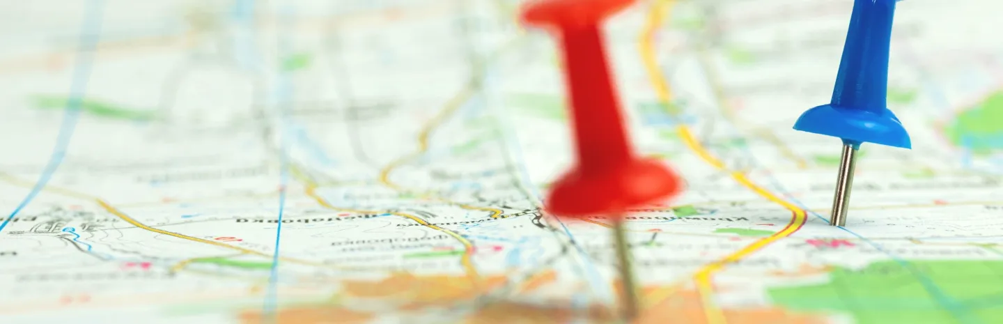 Map with many thumbtacks marking locations.