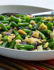 white bowl with green beans, egg and chopped onion
