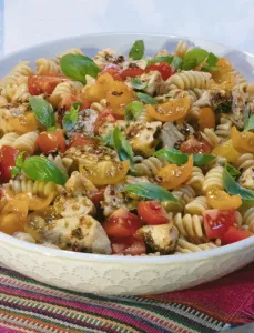 white bowl filled with tomato and chicken pasta salad