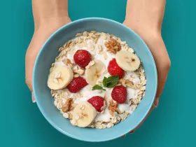 blue bowl of oatmeal with berries and bananas.