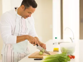 man chopping vegetables in bright kitchen