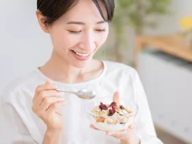 woman eating a small yogurt parfait out of a clear bowl
