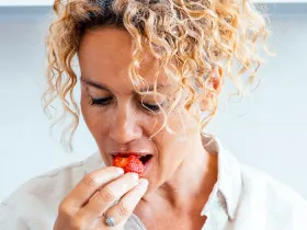 Woman taking a bite of a red berry