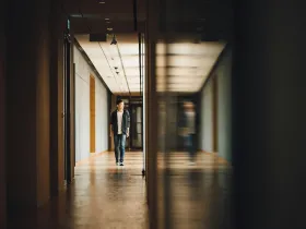 An adolescent boy walking alone down a school hallway