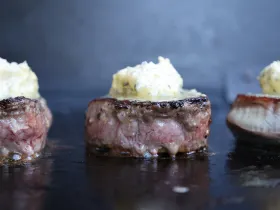 Eye fillet steaks on a grill topped with garlic butter