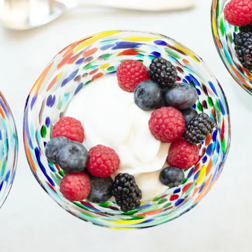 colorful glass bowl holding yogurt and various berries