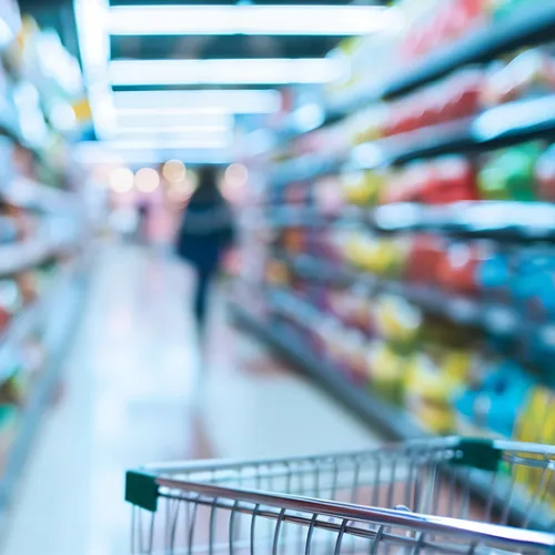 grocery cart in focus in the foreground with grocery store shelves out of focus in the background