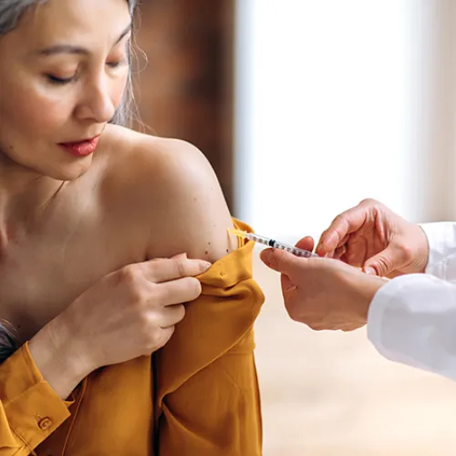 middle aged woman getting a vaccine in her arm