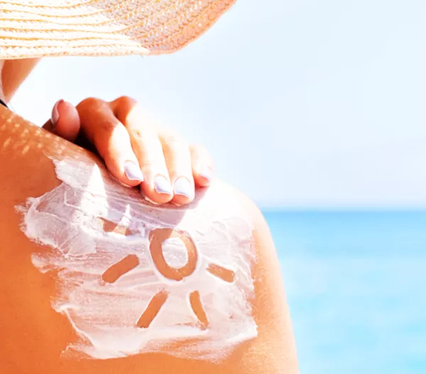 person rubbing sunscreen on their shoulder on a sunny day.