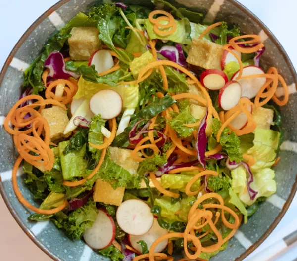 bowl of salad with greens and sliced vegetables
