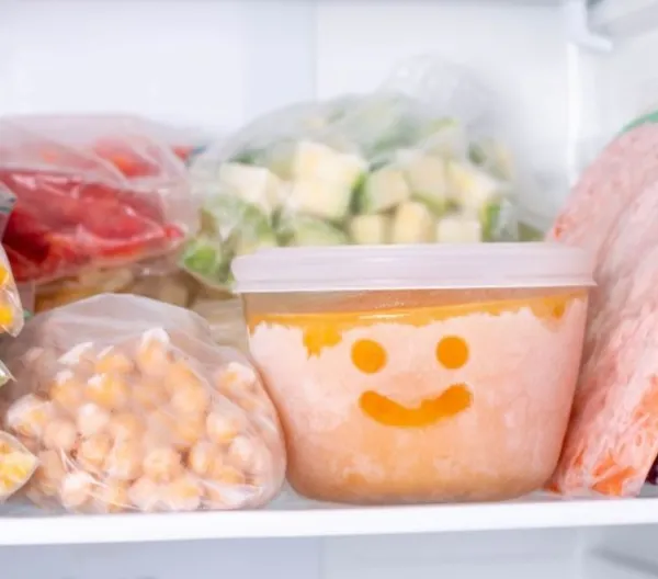 Frozen vegetables in a freezer. A bowl of frozen food with a smiley face drawn in the frost