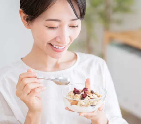 woman eating a small yogurt parfait out of a clear bowl