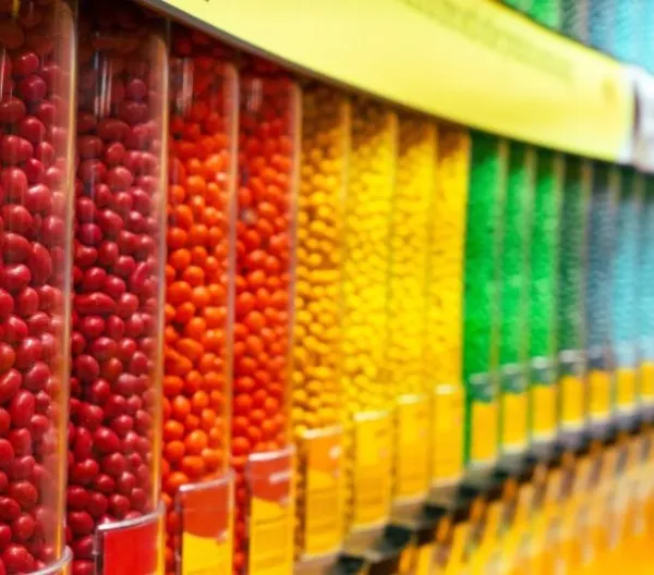 Colorful assortment of round candy drops in clear plastic containers arranged in a row.