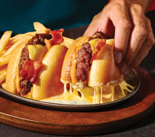 Applebee's O-M-Cheese Burger and fries with a hand picking up on half of the burger