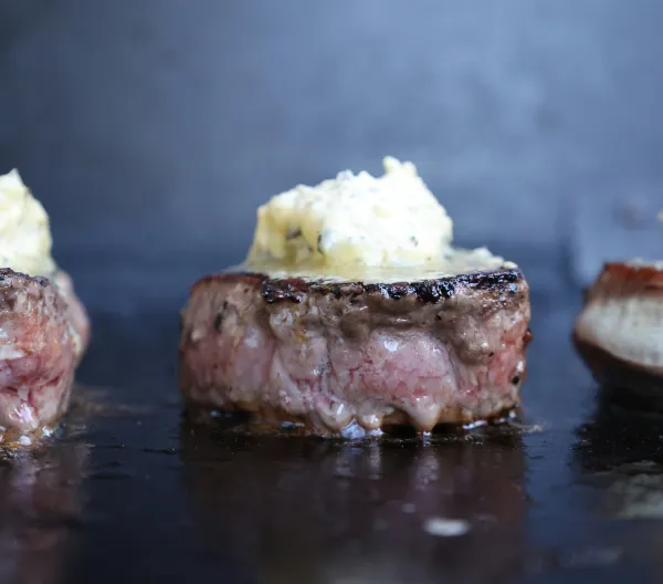 Eye fillet steaks on a grill topped with garlic butter