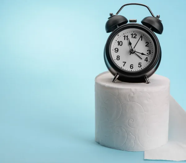 alarm clock sitting on a roll of toilet papper