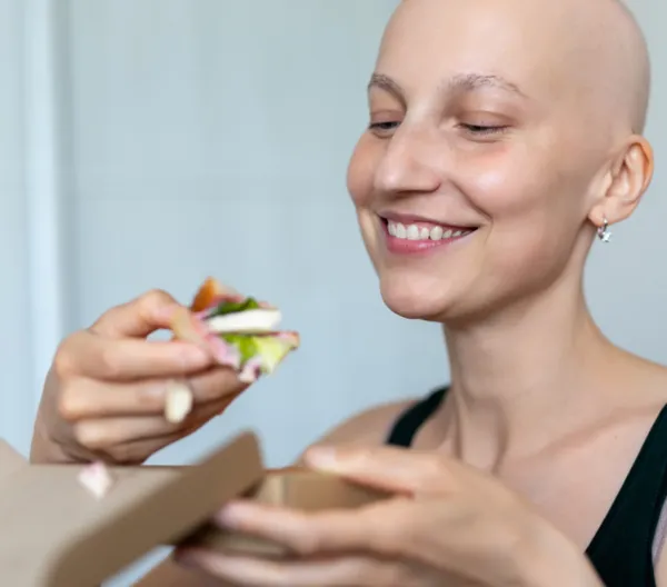 bald woman eating a salad with tofu in it