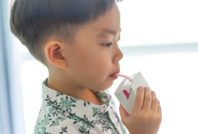 young child sipping from a juice box with straw