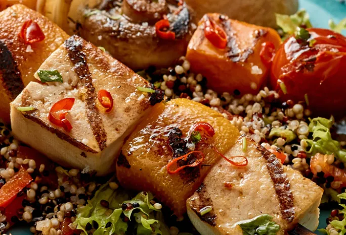 Tofu cubes on skewers with sauce drizzled all over