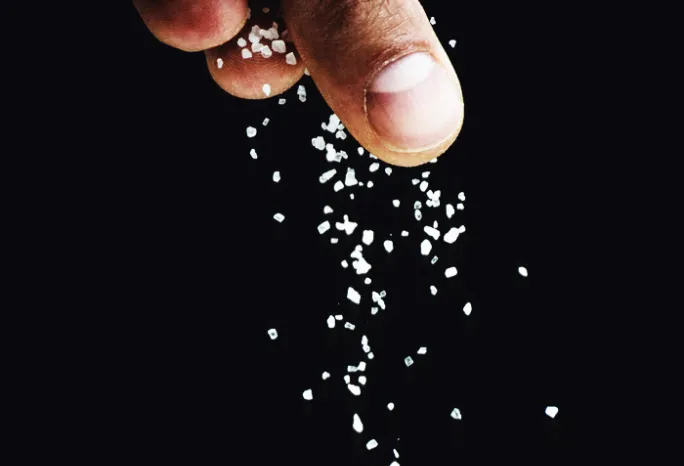 fingers sprinkling salt on a black background