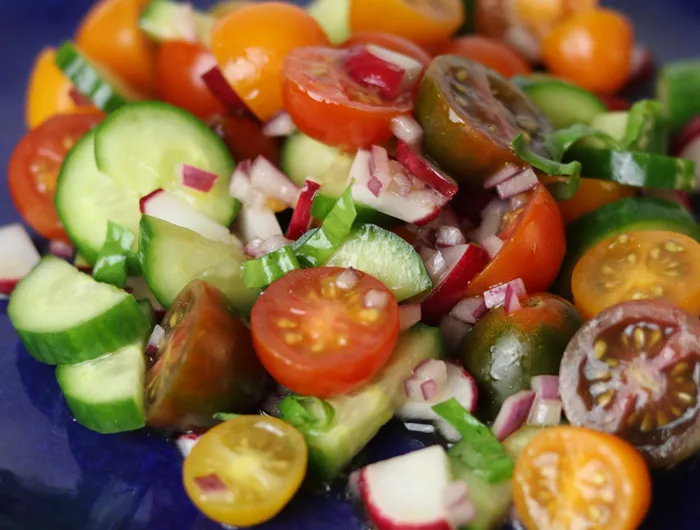tomato, cucumber, radish salad on blue plate.