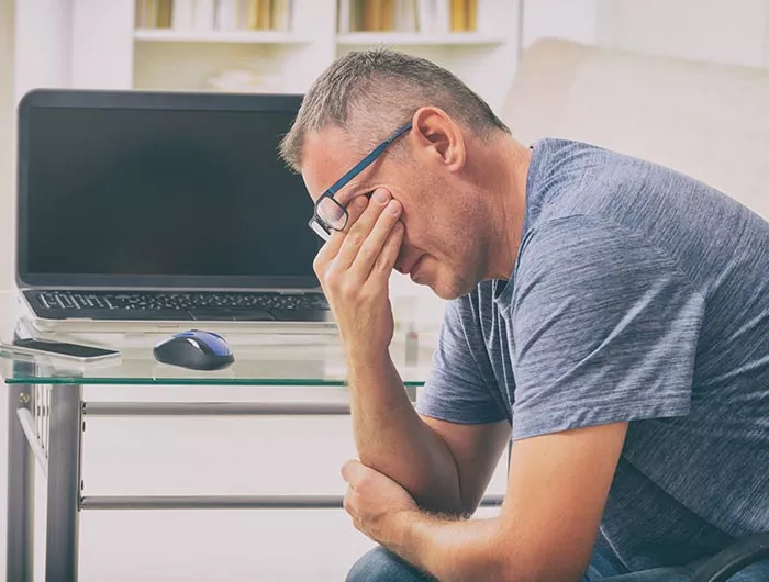 man sitting down and rubbing eyes