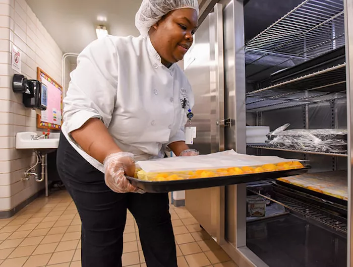 Cafeteria staff place fruit cups in fridge