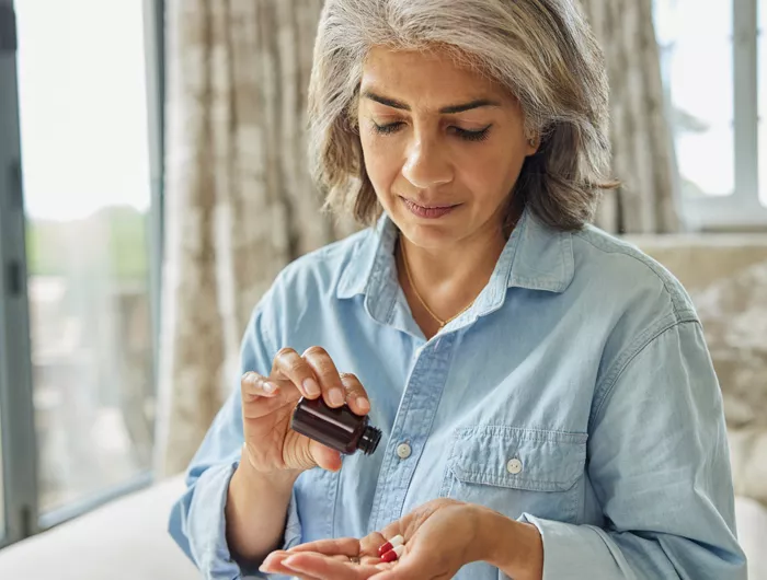 Woman pouring supplements into her hand from bottle