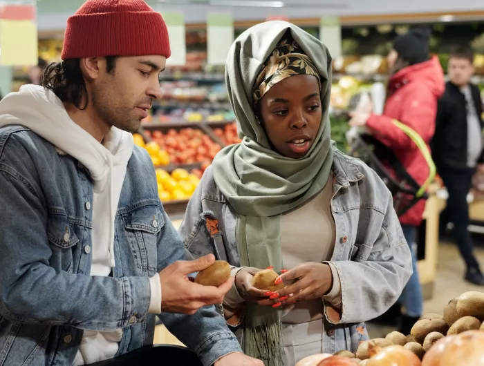 A young man and woman shopping in a grocery store produce aisle