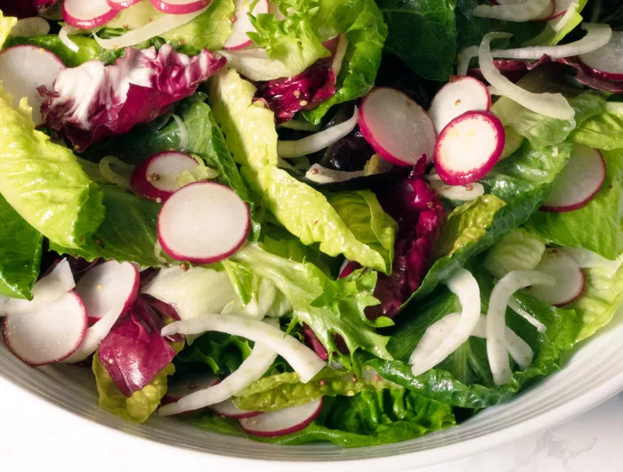 close up on bowl of salad with mixed greens and radish slices