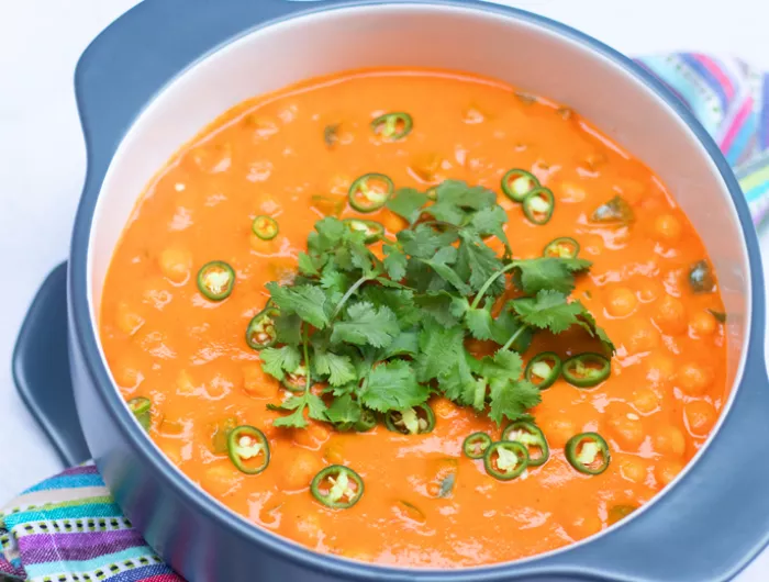 large blue pot of paprika chickpeas with green garnishes