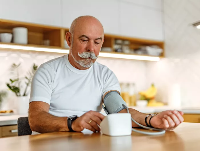 Man taking his blood pressure in the kitchen