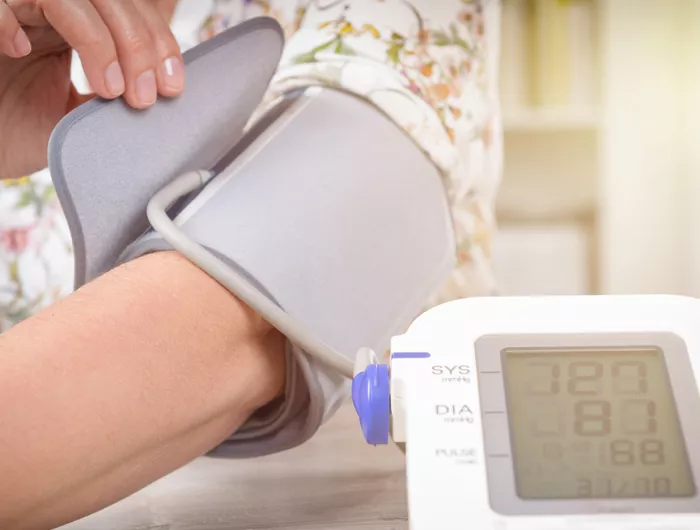 person fastening a blood pressure monitor on their arm
