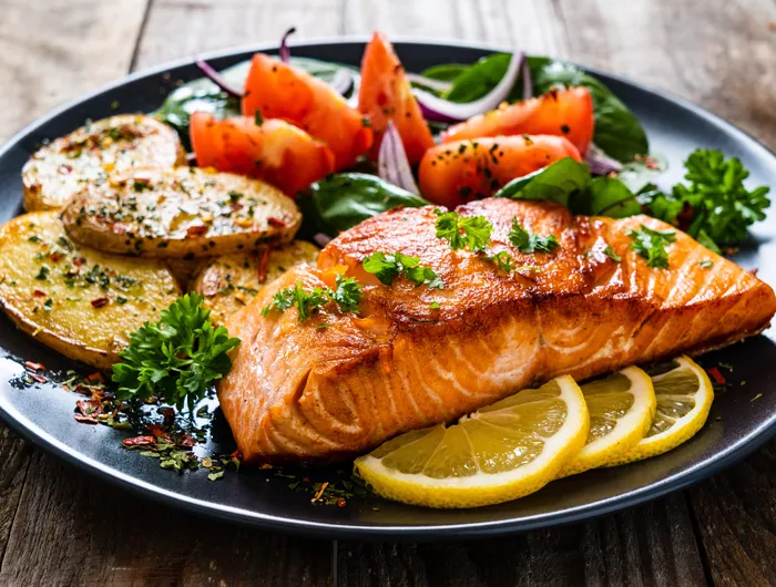 plate with cooked salmon tomatoes and potatoes
