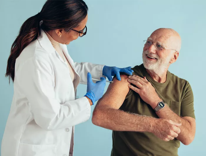 doctor giving an older man a vaccine in his arm