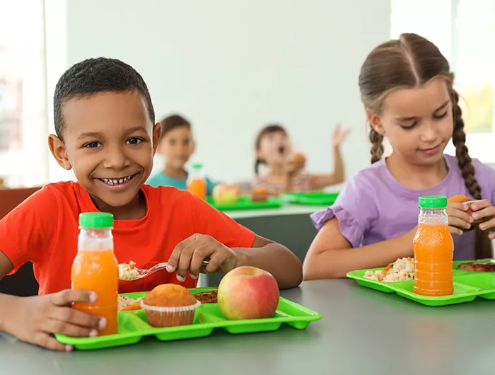 Children sitting at table and eating healthy food during break at school