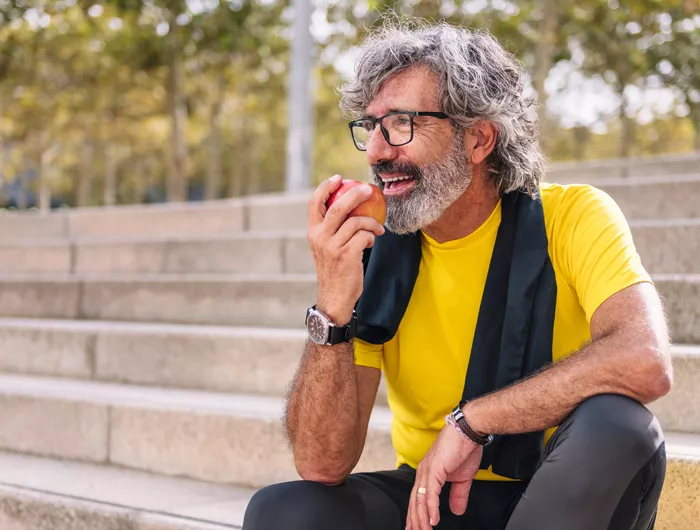man sitting on steps outside eating an apple