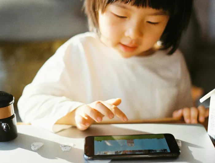 A young child watches cartoons on a small tablet