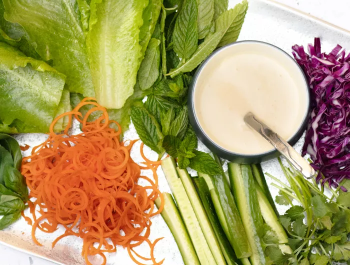 tray filled with different lettuce and chopped vegetables and sauce