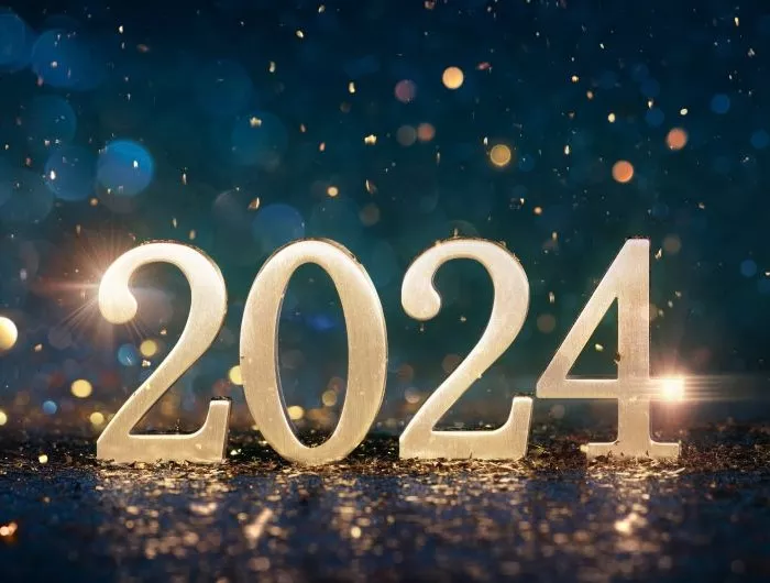 2024 in gold numerals on a reflective surface in front of deep blue bokeh background