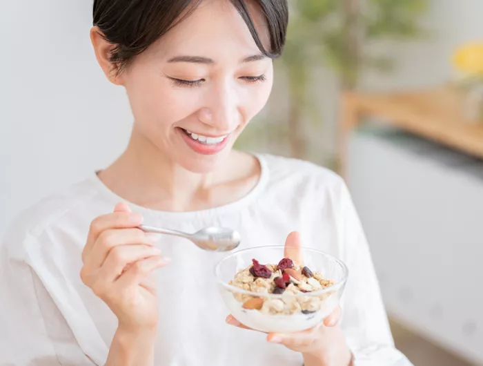 woman eating a small yogurt parfait out of a clear bowl