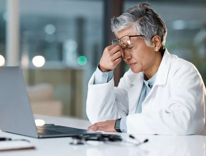 Doctor experiences headache while reviewing data on a laptop