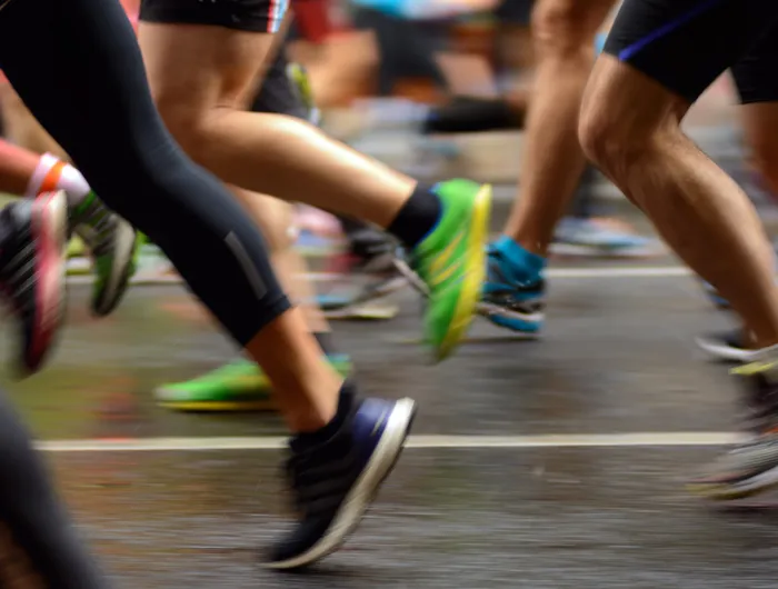 legs and feet of runners passing on a road