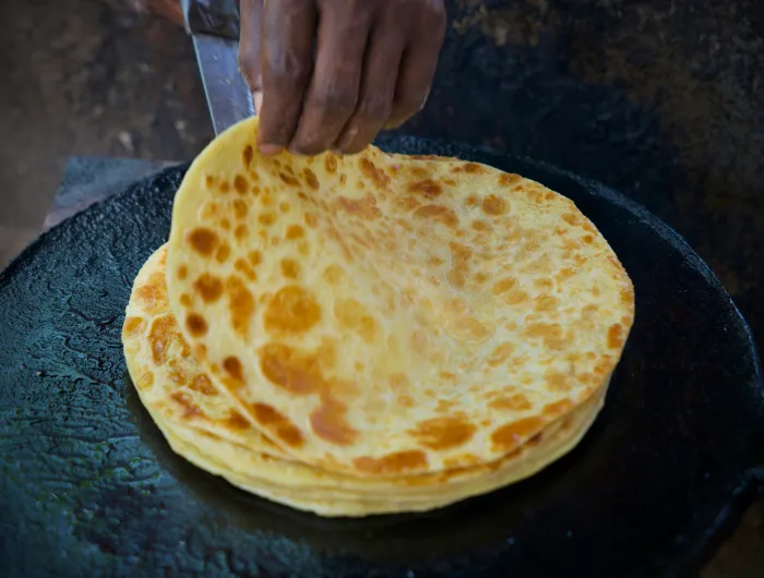 Corn tortillas being heated on a flat griddle