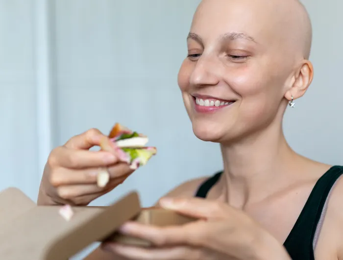 bald woman eating a salad with tofu in it