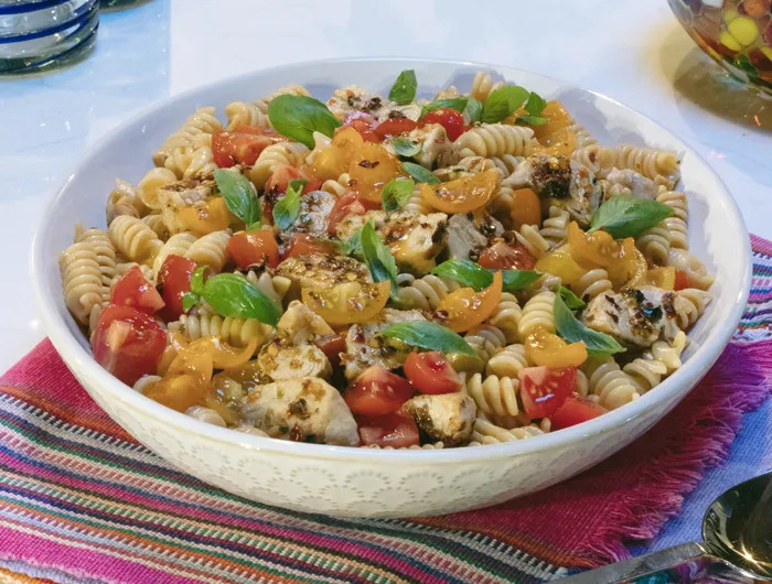 white bowl filled with tomato and chicken pasta salad