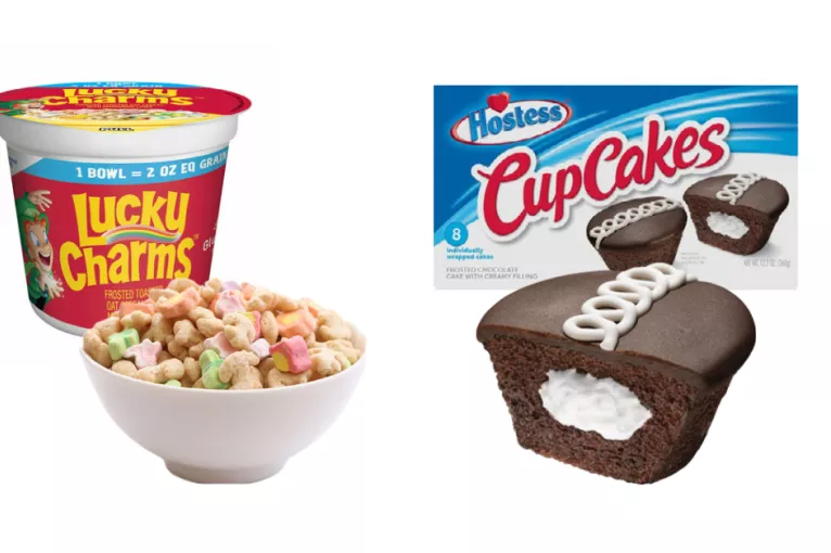 A bowl of Lucky Charms cereal next to a Hostess cupcake