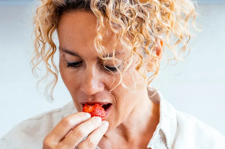 Woman taking a bite of a red berry