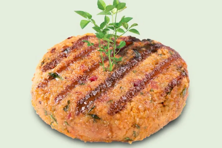 grilled plant based burger patty with green sprout coming out